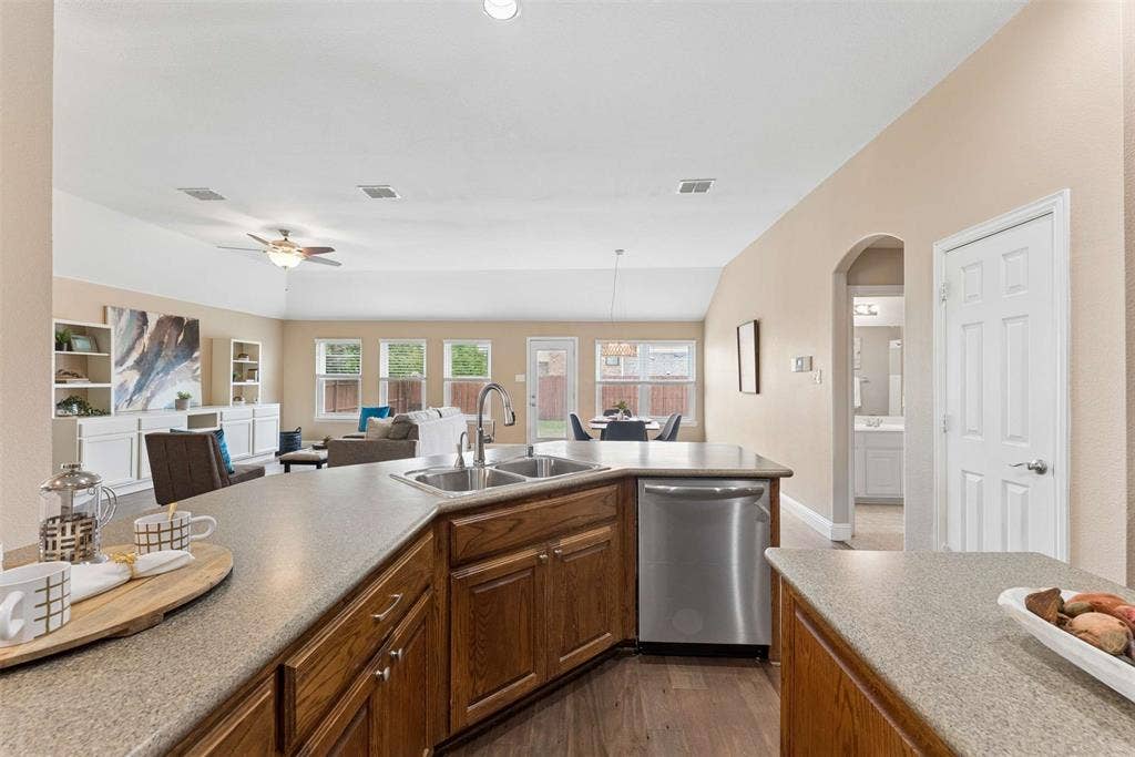 1221 Amistad Drive, Prosper, TX 75078 The kitchen features a double basin stainless steel sink, a stainless steel dishwasher, and wooden cabinetry