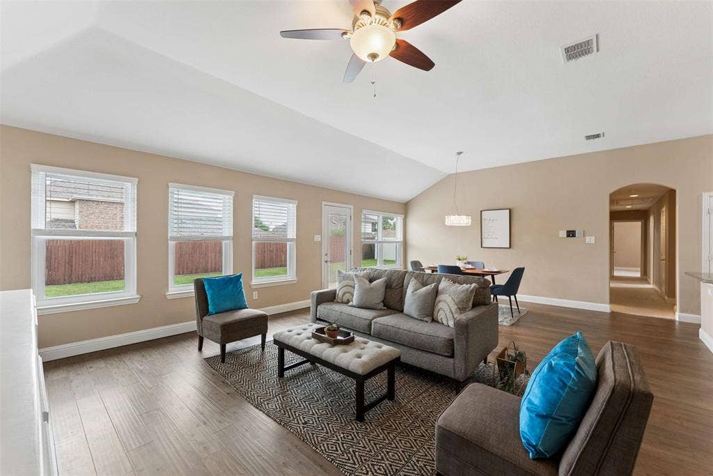 1221 Amistad Drive, Prosper, TX 75078 Spacious living area featuring vaulted ceilings, hardwood flooring, and neutral wall tones