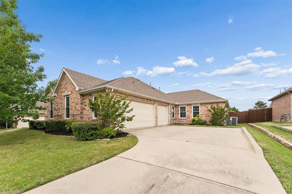 1221 Amistad Drive, Prosper, TX 75078 Brick exterior with light mortar, two garage doors, and a concrete driveway