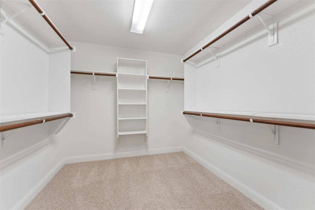 1221 Amistad Drive, Prosper, TX 75078 This spacious closet features carpeting, built-in shelving, and hanging rods with integrated shelving