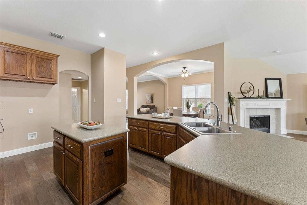 1221 Amistad Drive, Prosper, TX 75078 The kitchen features a double basin sink with a gooseneck faucet, ample counter space, and wood cabinetry
