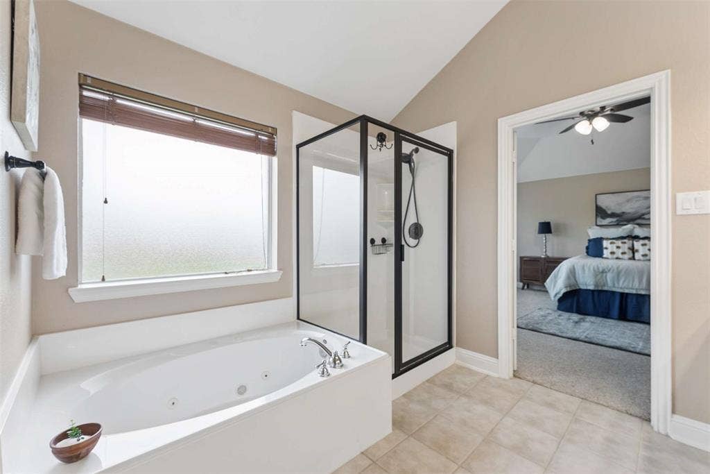 1221 Amistad Drive, Prosper, TX 75078 Bathroom featuring a white soaking tub with jets, a separate shower with black framing, and neutral toned tiled flooring