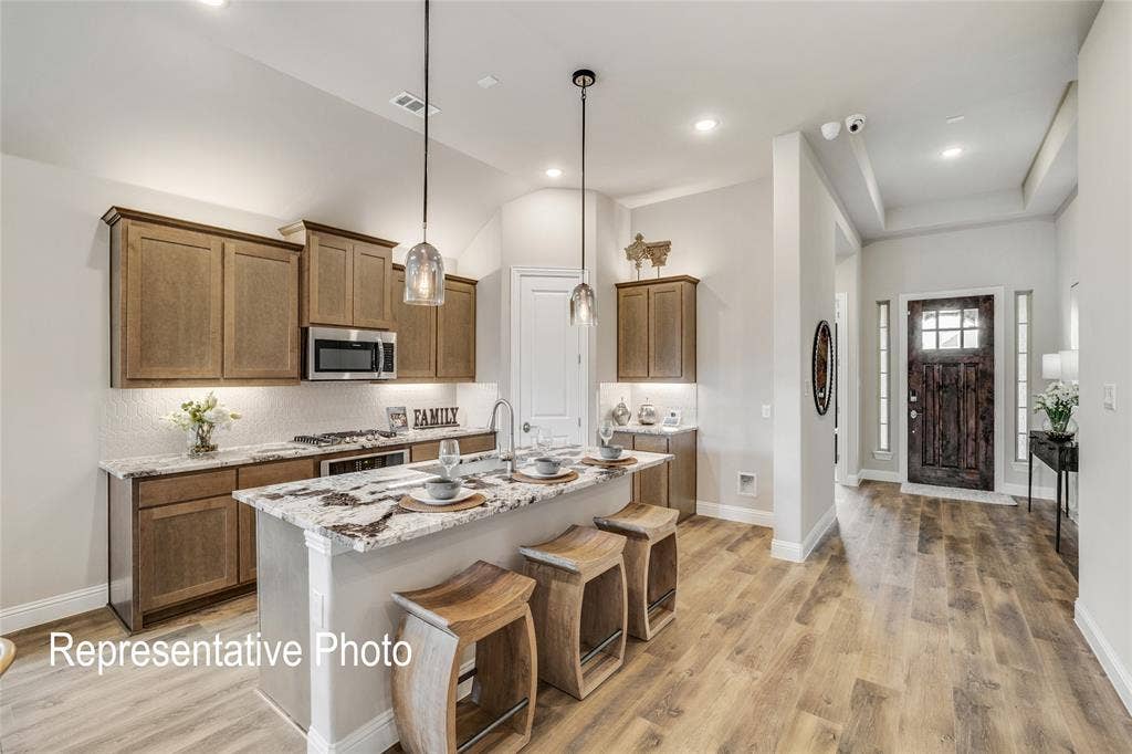 1415 Odette Drive, Arlington, TX 76013 The kitchen features a spacious island with a light-colored countertop, wooden cabinetry, and stainless steel appliances