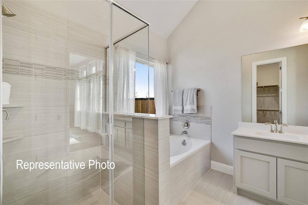 1415 Odette Drive, Arlington, TX 76013 This bathroom features a contemporary design with a glass-enclosed shower, a built-in bathtub, and a vanity with a white countertop