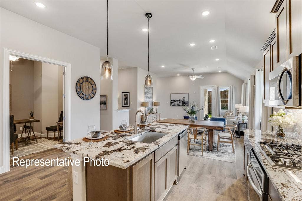 1415 Odette Drive, Arlington, TX 76013 This expansive kitchen and living area features wood flooring, a kitchen island with a sink, stainless steel appliances, and recessed lighting