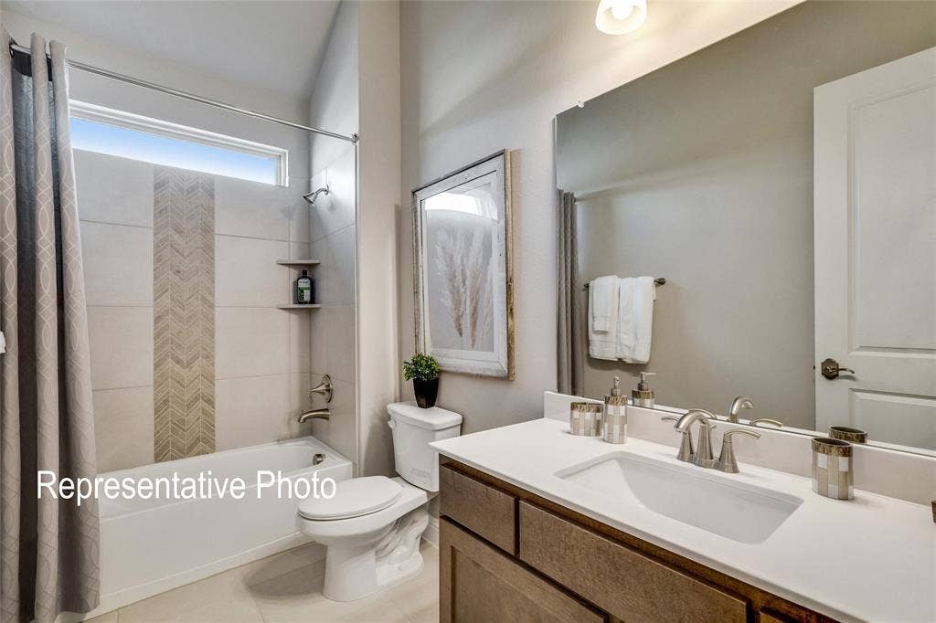 1415 Odette Drive, Arlington, TX 76013 Bathroom featuring a bathtub with a tiled surround, a vanity with a white countertop and rectangular sink, and a large mirror