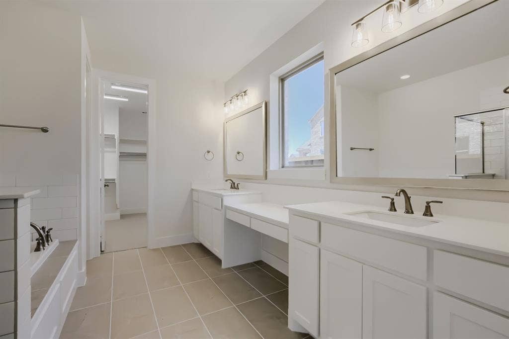 828 Stone Grove Road, Lavon, TX 75166 Bathroom featuring dual vanities with white cabinetry and countertops, framed mirrors, and bronze-finish fixtures