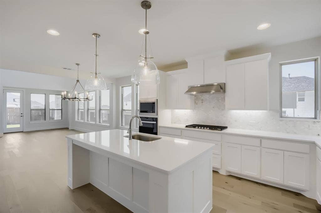 828 Stone Grove Road, Lavon, TX 75166 Modern kitchen featuring a large island with sink, white cabinetry, integrated stainless steel appliances, and a gas cooktop