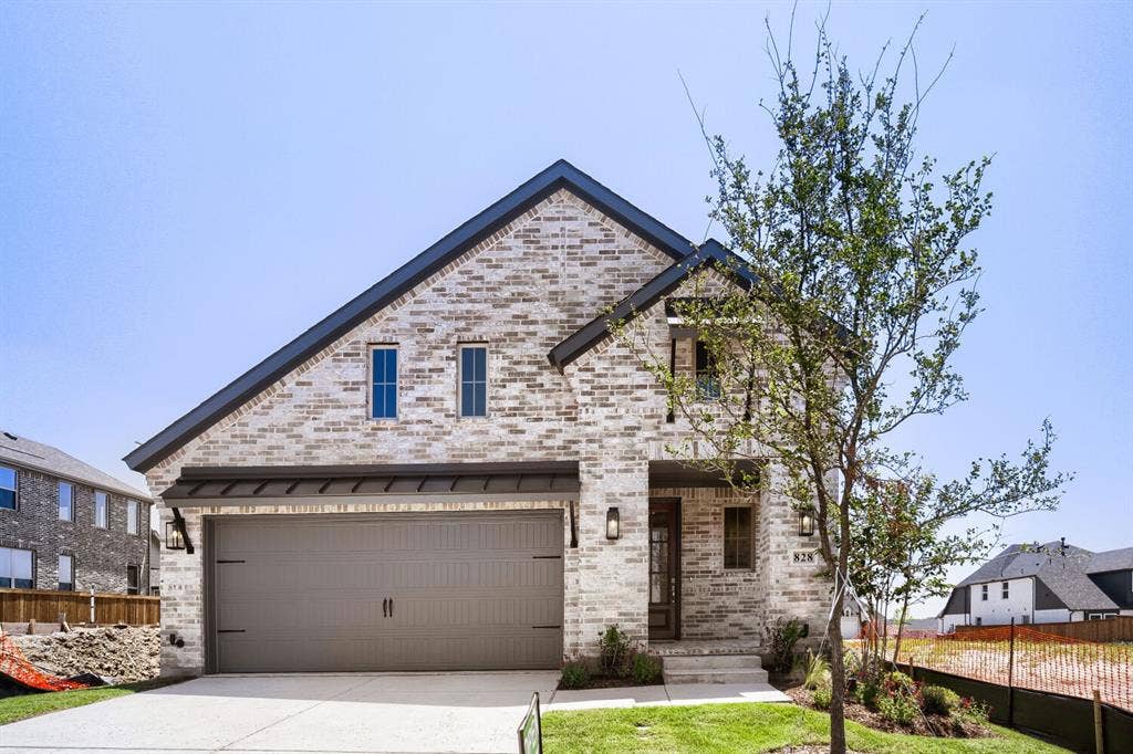 828 Stone Grove Road, Lavon, TX 75166 Contemporary home featuring a light-colored brick exterior, dark asphalt shingle roof, and a two-car garage with a dark gray door
