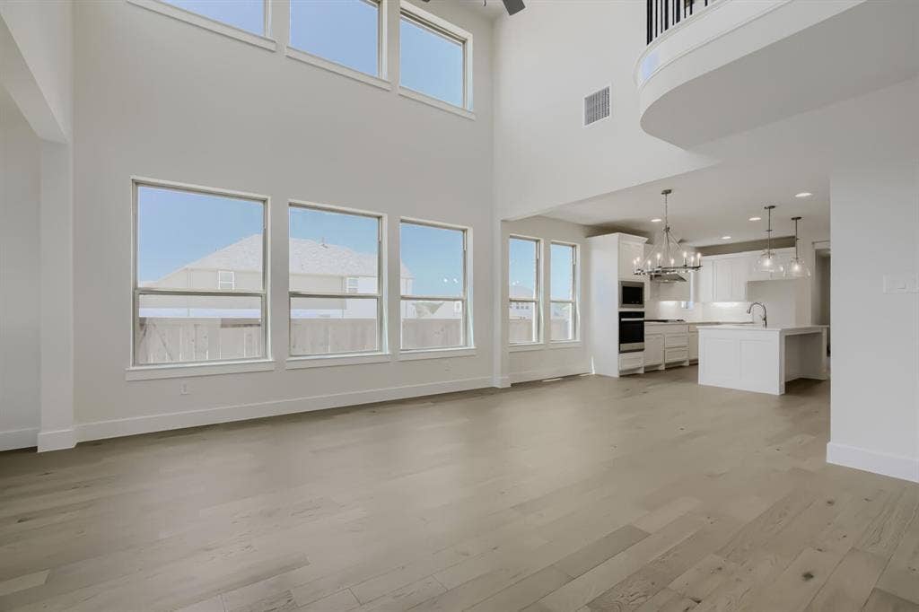 828 Stone Grove Road, Lavon, TX 75166 Open-concept living area featuring a two-story ceiling, light wood-finish flooring, and an abundance of natural light through multiple windows