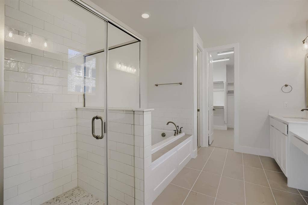 828 Stone Grove Road, Lavon, TX 75166 Spacious bathroom featuring a glass-enclosed shower with white subway tile, a built-in soaking tub, and neutral-toned floor tiling