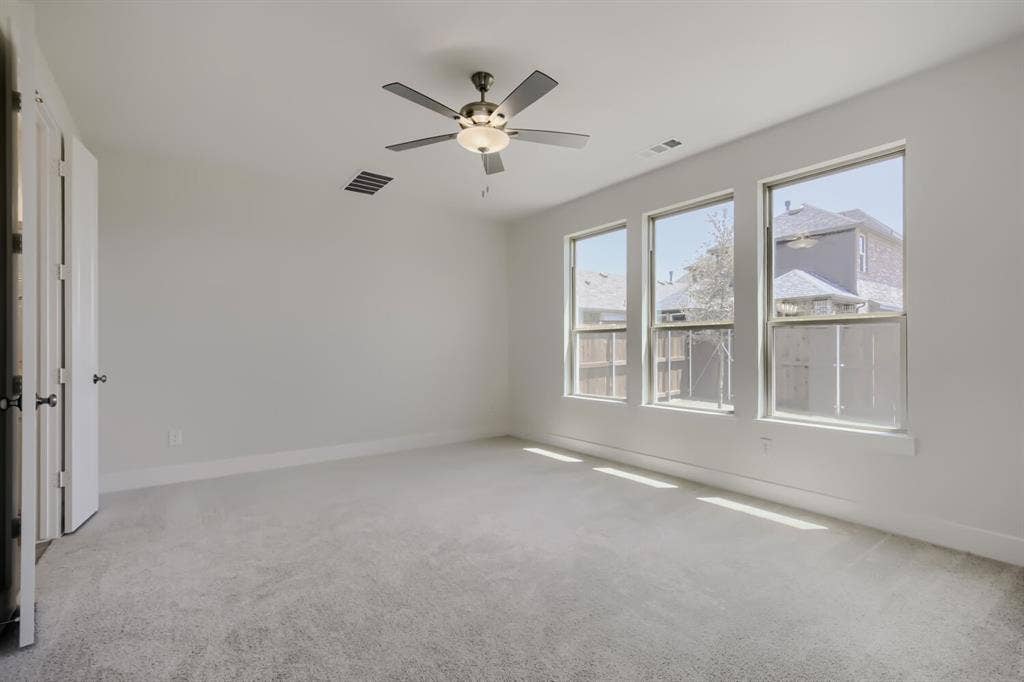 828 Stone Grove Road, Lavon, TX 75166 Spacious room featuring three large windows, light gray carpeting, and a ceiling fan with integrated lighting