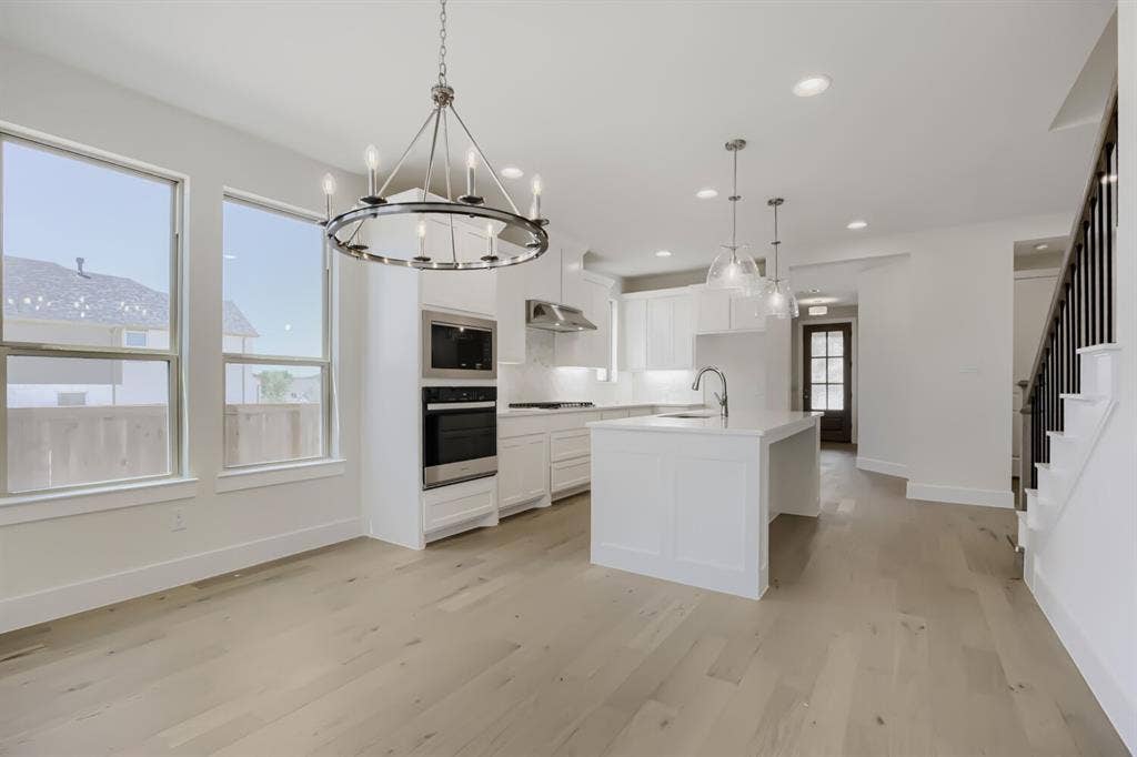 828 Stone Grove Road, Lavon, TX 75166 Open-concept living area featuring light wood-finish flooring and a contemporary chandelier