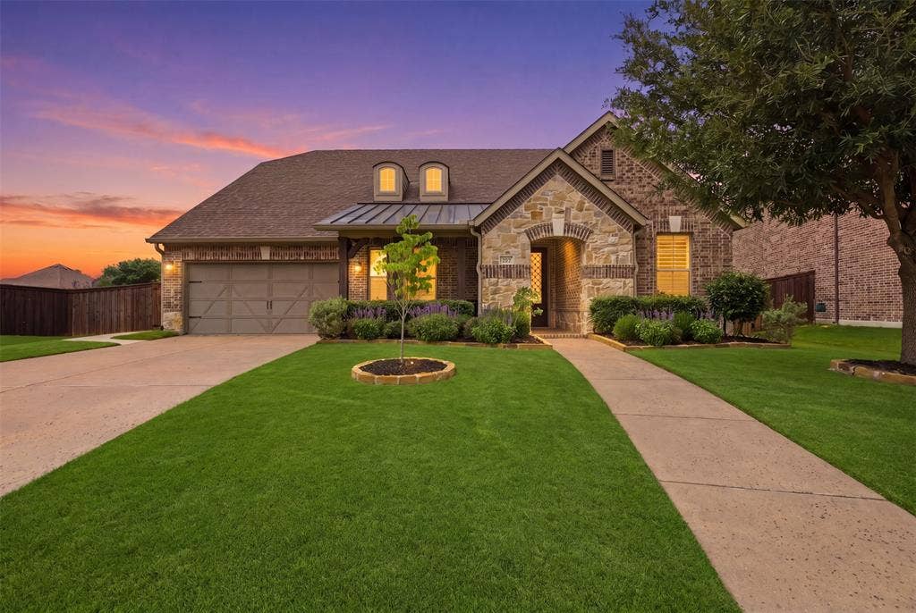 11414 Alejandra Lane, Frisco, TX 75035 Traditional-style residence featuring a brick and stone facade, arched entryway, and a prominent two-car garage