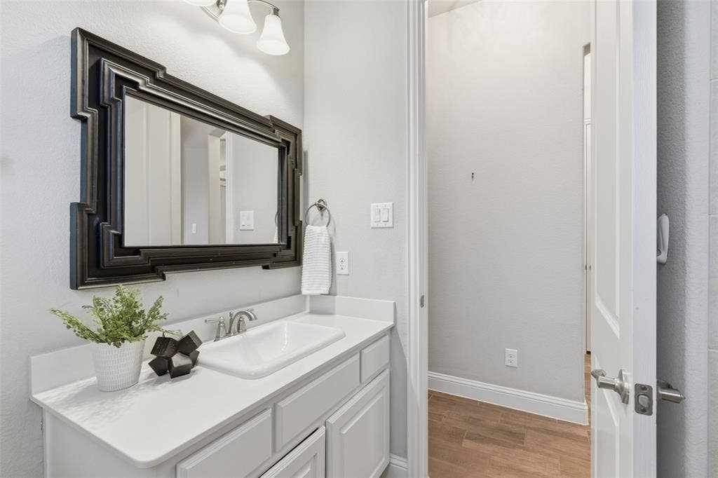 11414 Alejandra Lane, Frisco, TX 75035 First floor secondary bathroom vanity featuring a white countertop, undermount sink with chrome faucet, and white cabinetry