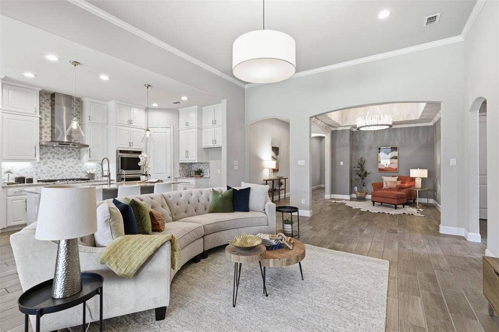 11414 Alejandra Lane, Frisco, TX 75035 Open-concept living space with wood-finish flooring, a white kitchen, and an arched entryway