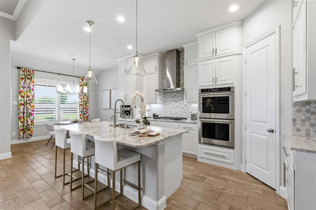 11414 Alejandra Lane, Frisco, TX 75035 Modern kitchen with wood-finish tile flooring and an oversized island featuring a light-toned countertop