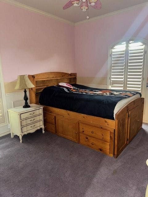 Bedroom featuring ornamental molding, ceiling fan, and dark colored carpet