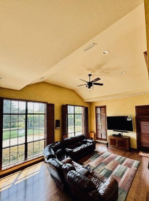 Living room featuring visible vents, ceiling fan, wood finished floors, and lofted ceiling