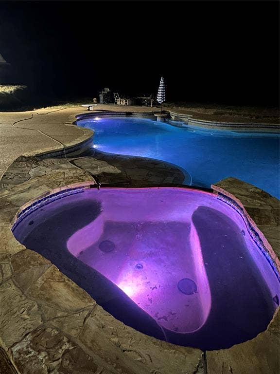 Outdoor pool featuring a patio area and an in ground hot tub