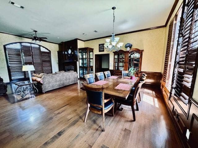 Dining space featuring crown molding, visible vents, a wainscoted wall, and wood finished floors