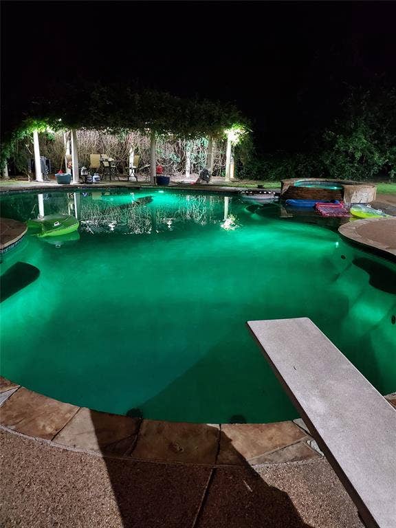 Pool featuring a diving board and a hot tub