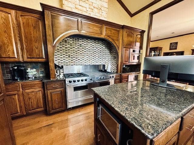 Kitchen featuring crown molding, tasteful backsplash, double oven range, and light wood finished floors