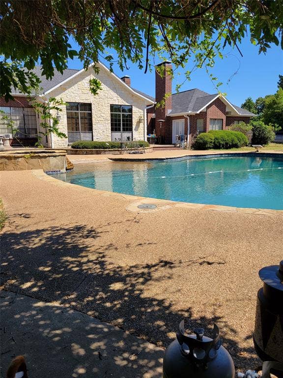 View of pool with a diving board, a patio area, and a fenced in pool