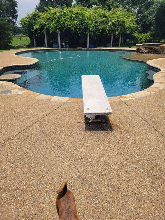 View of pool featuring a patio, a pool with connected hot tub, and a diving board