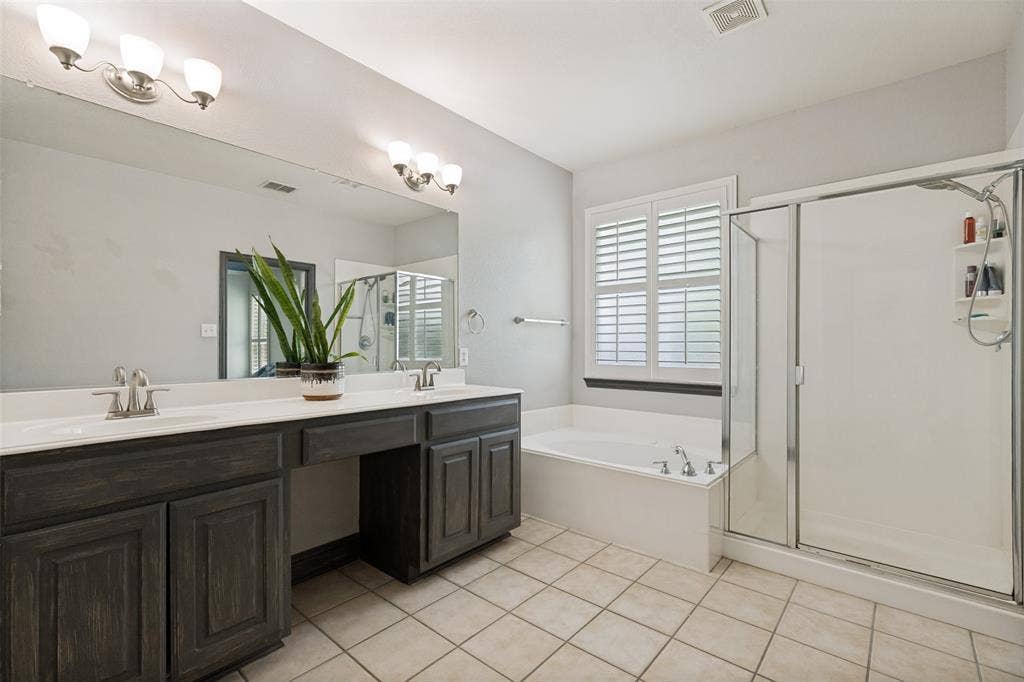 Tiled master bathroom equipped with jetted tub, separate oversized shower, dual sinks, vanity and walk-in closet.