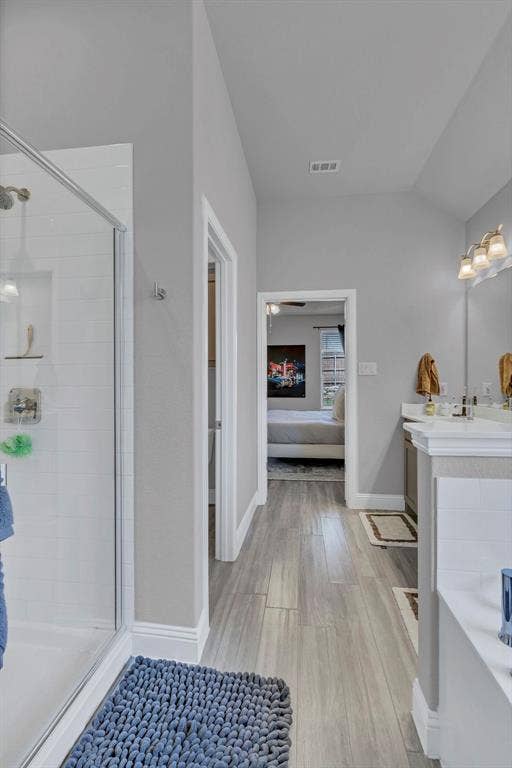 1000 Westwood Lane, Argyle, TX 76226 The bathroom features a glass-enclosed shower, a double vanity with a light fixture, and wood-look flooring