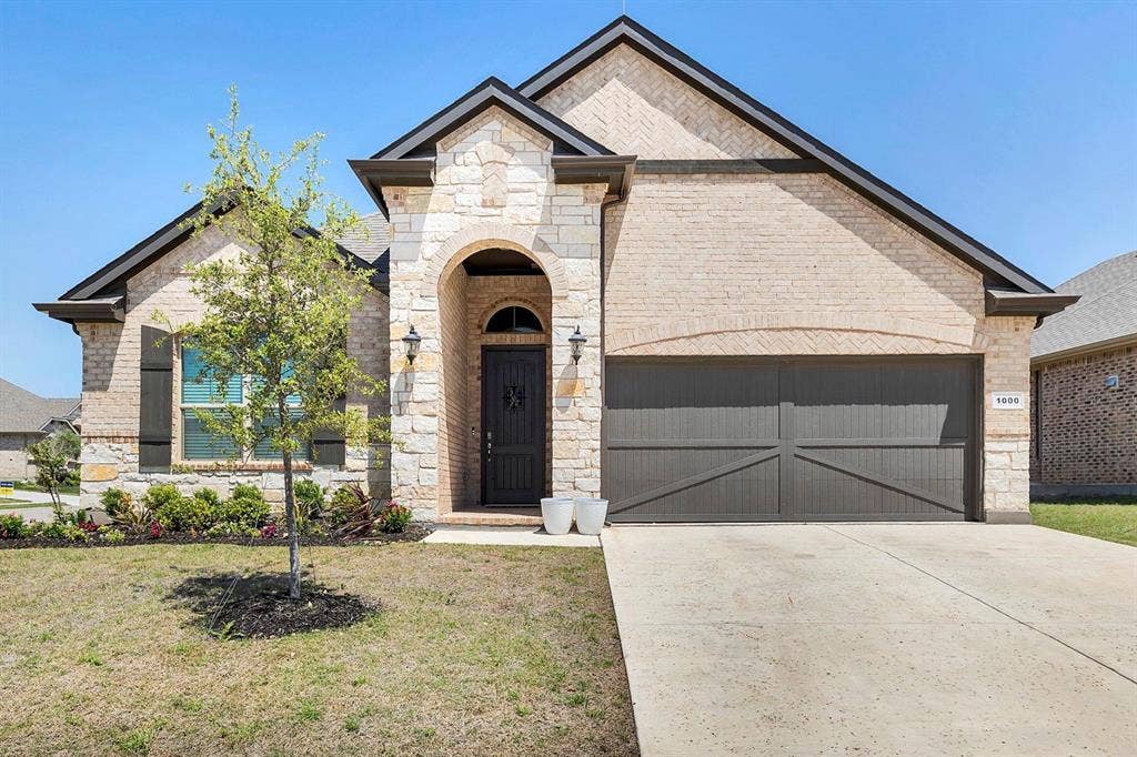 1000 Westwood Lane, Argyle, TX 76226 The property features a brick and stone facade, an arched entryway, and a dark wood front door