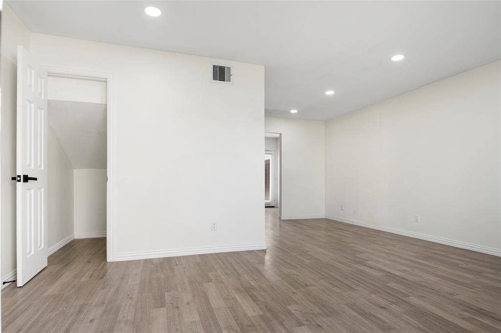 Spacious room featuring light wood-finish flooring, recessed lighting, and white baseboards