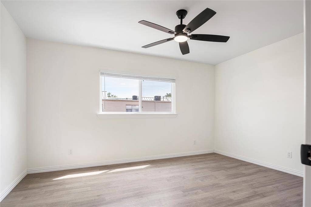 Bright room featuring a window with white blinds, wood-finish flooring, a ceiling fan with integrated lighting, white walls, and white trim