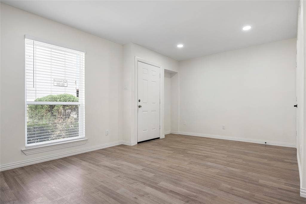 Spacious room featuring wood-finish flooring, white walls, and recessed lighting