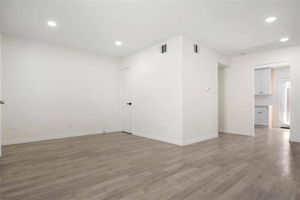 Spacious room featuring wood-finish flooring, white baseboards, and recessed lighting