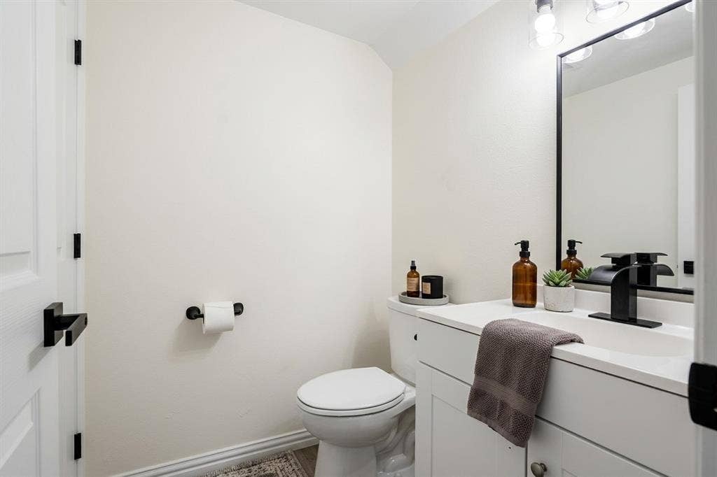 White vanity with integrated sink, black rectangular framed mirror, matte black faucet, and coordinating black hardware
