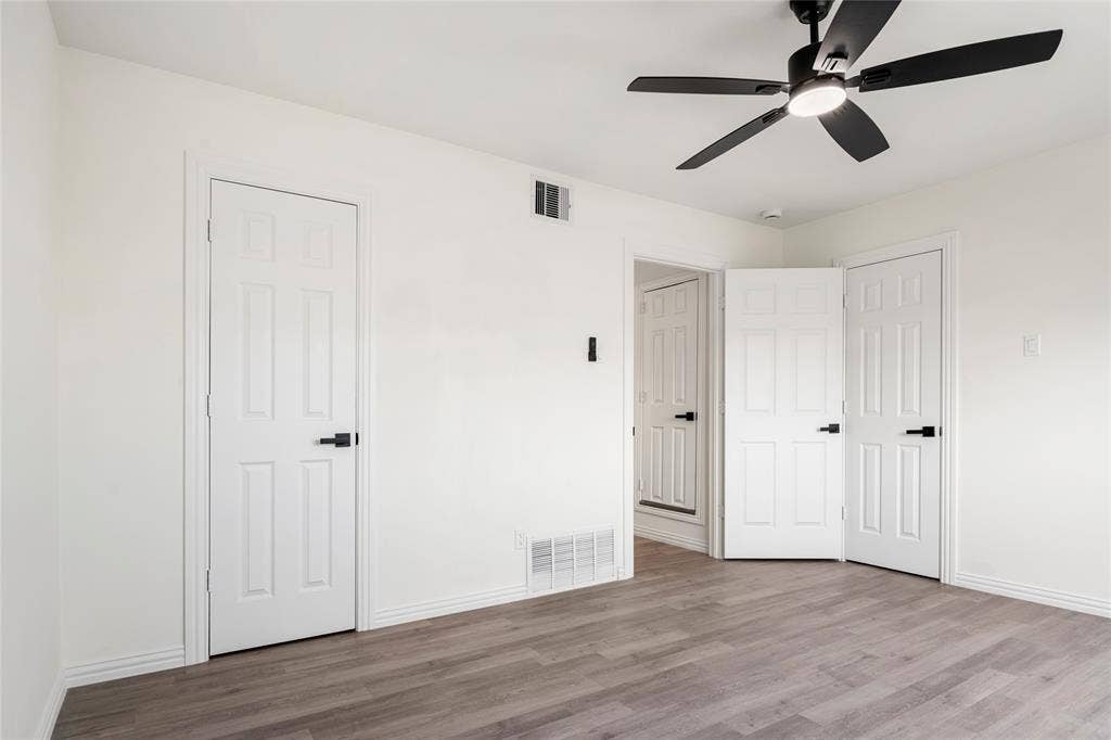 Room with wood-finish flooring, white painted walls, and white baseboards