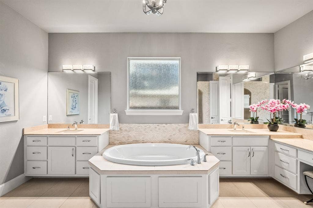 1640 Stillhouse Hollow Drive, Prosper, TX 75078 The primary bathroom has split vanity areas plus another vanity with seating. The rain glass window invites light. There is a garden tub and separate large shower.