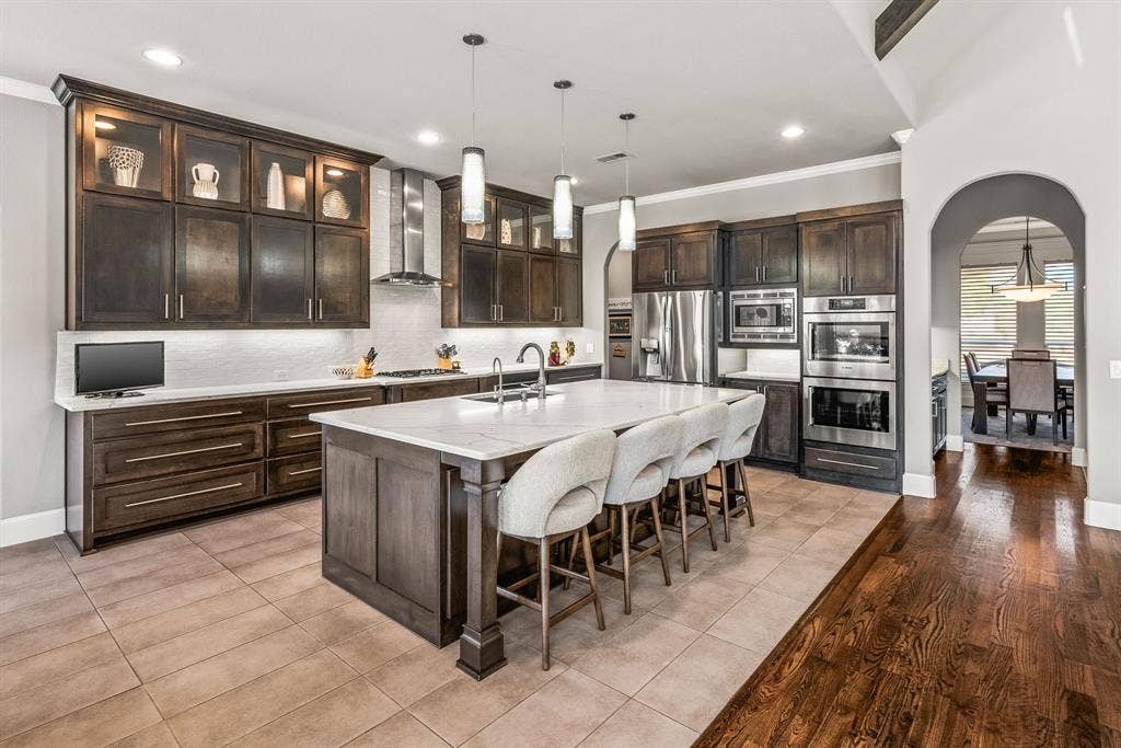 1640 Stillhouse Hollow Drive, Prosper, TX 75078 Quality, quality throughout from Bosch stainless appliances, custom built cabinets with glass lit display topper, under cabinet lights, pull out drawers , quartz countertop, island with counter seating. Around the corner is a large pantry.