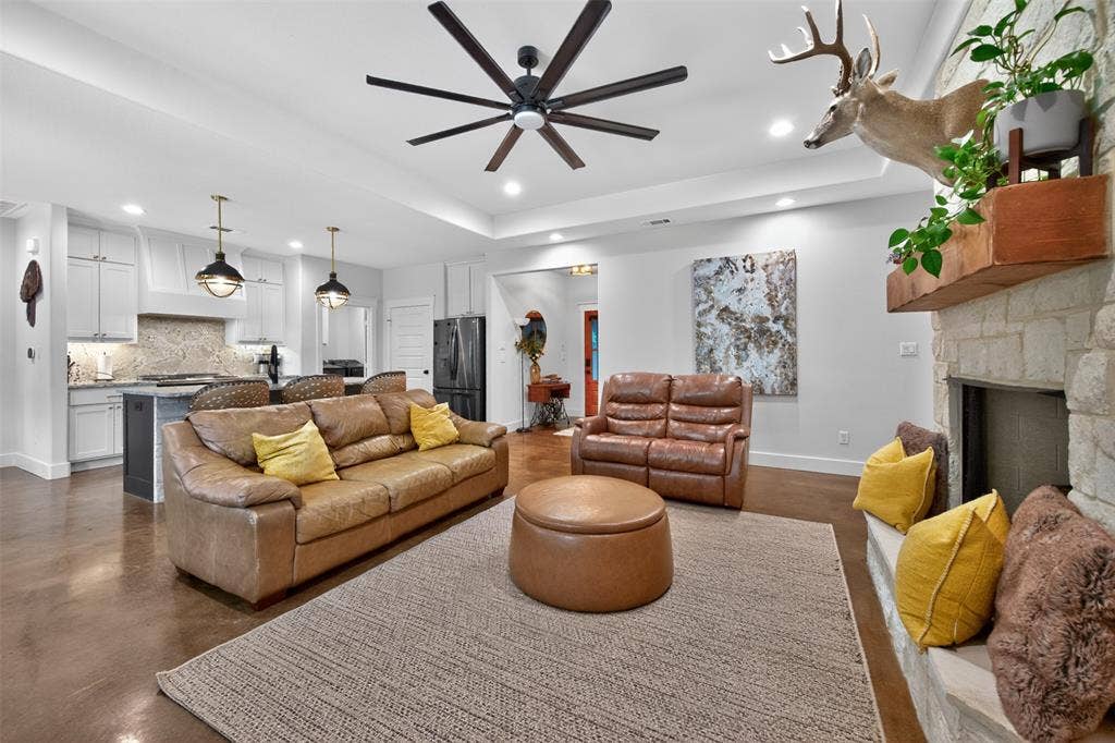 6371 Mill Run Road, Athens, TX 75751 The open-concept living area features a stone-clad fireplace, a ceiling fan, and recessed lighting