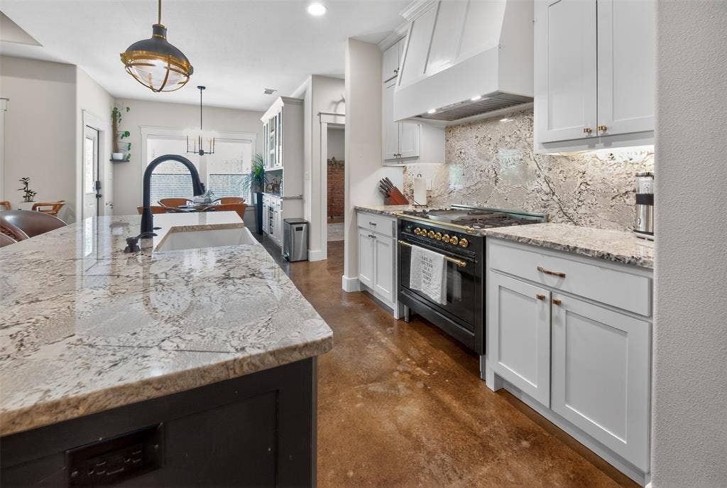6371 Mill Run Road, Athens, TX 75751 The kitchen features an island with a light-colored granite countertop and sink, a black faucet, and white cabinetry