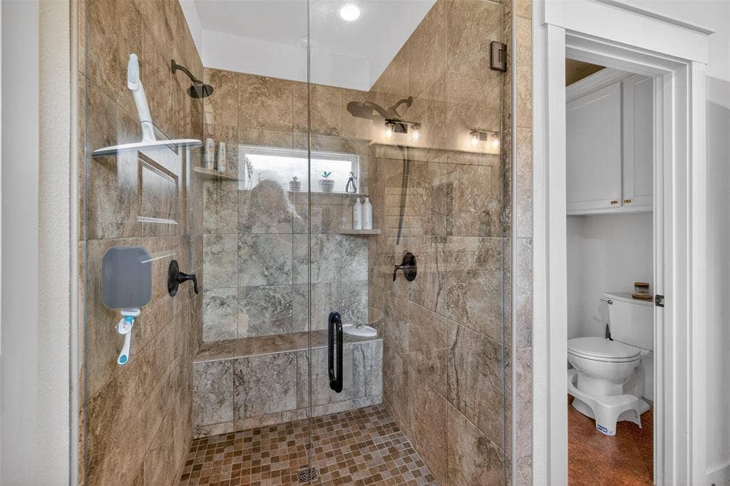 6371 Mill Run Road, Athens, TX 75751 The bathroom features a spacious shower with glass enclosure, tiled walls and floor, built-in shelving, and a shower bench