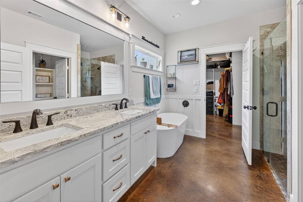 6371 Mill Run Road, Athens, TX 75751 The bathroom features a double vanity with granite countertops, a freestanding bathtub, and a glass-enclosed shower