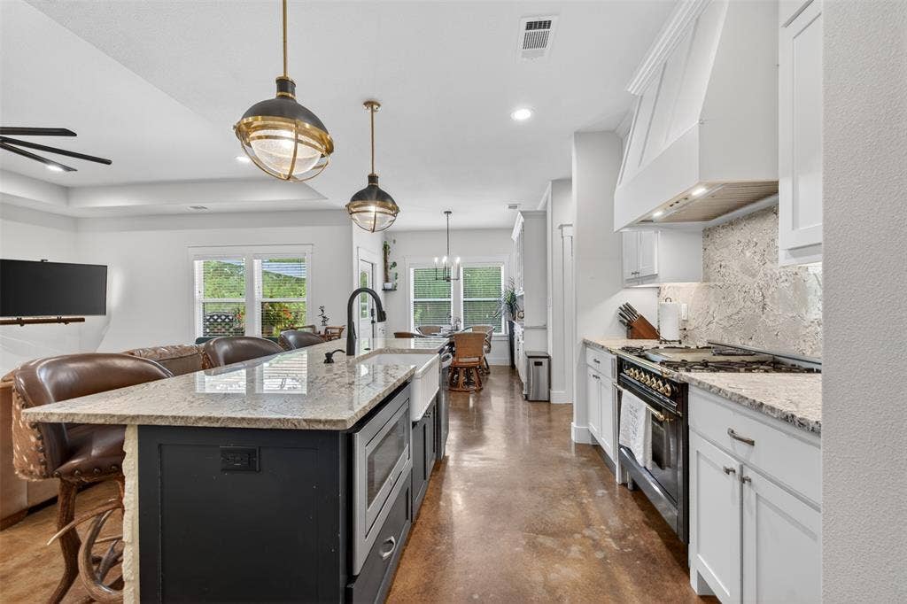 6371 Mill Run Road, Athens, TX 75751 The kitchen features white cabinetry, a large kitchen island with a farmhouse sink, granite countertops, and an ILVE custom commercial range with a matching hood