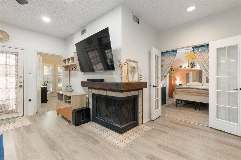 5590 Spring Valley Road, #C102, Dallas, TX 75254 cozy corner wood burning fireplace centrally located between living and dining spaces