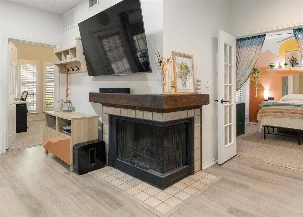 5590 Spring Valley Road, #C102, Dallas, TX 75254 cozy corner wood burning fireplace centrally located between living and dining spaces