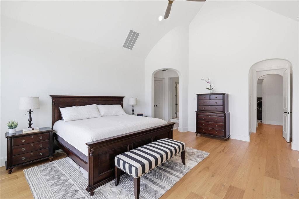 Spacious room featuring vaulted ceilings, wood-finish flooring, and white painted walls