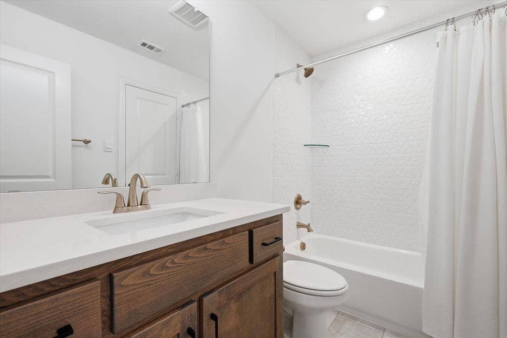 Bathroom featuring a wood-finish vanity with a white countertop and integrated sink, brushed nickel faucet, and a large mirror