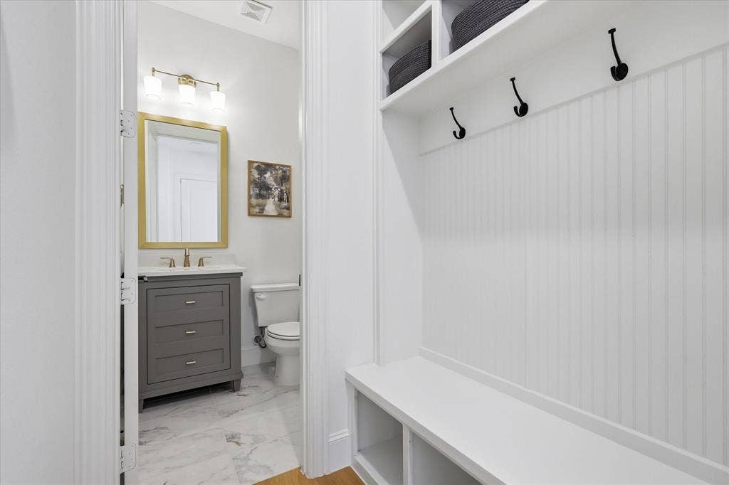 Entryway mudroom with white beadboard wall paneling, built-in bench seating, and overhead storage shelves